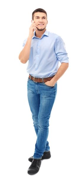 Young man talking on cell phone against white background - Foto, immagini