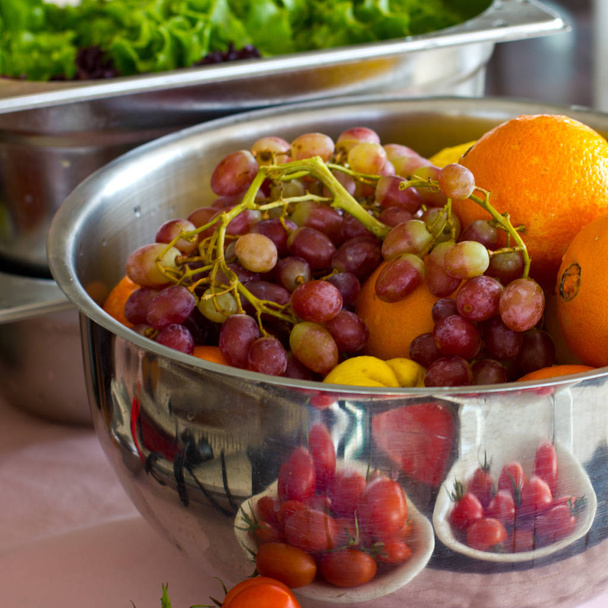 Fresh fruit grapes, orange in a silver bowl. Fresh greens, lettu - Photo, Image