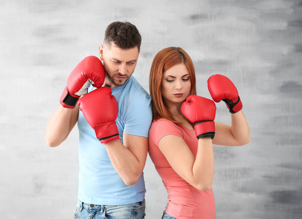 Angry couple in boxing gloves on grey background - Photo, Image
