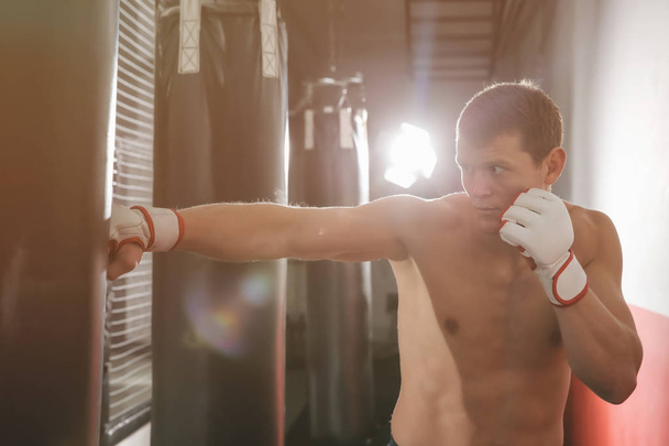 Male boxer training with punching bag in gym - Фото, зображення