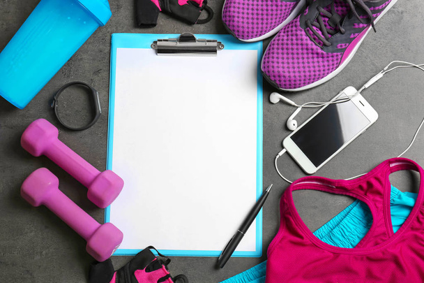 Clipboard with blank paper for exercise plan and gym stuff on grey background. Flat lay composition - Foto, Bild