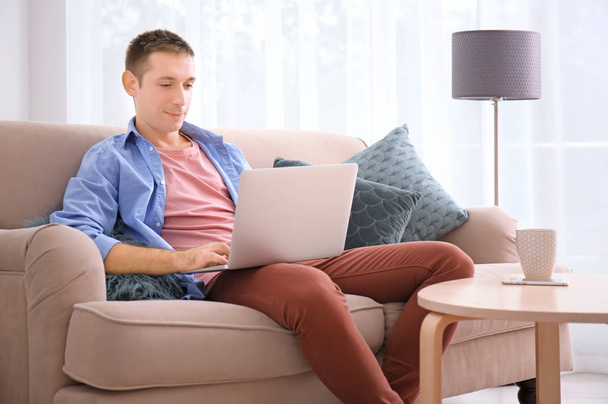 Young man in casual clothes using laptop at home - Foto, Imagen