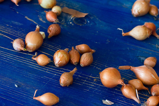 Ανεπεξέργαστα κρεμμύδια σε ένα μπλε ξύλινο παλιό σκάφους - Φωτογραφία, εικόνα