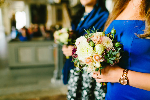 Close-Up photo of koszorúslányok holding csokrok virágok a templomban volt az esküvő. Grafika - Fotó, kép