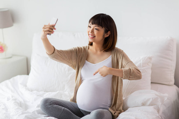 těhotná žena selfie pomocí smartphone doma - Fotografie, Obrázek