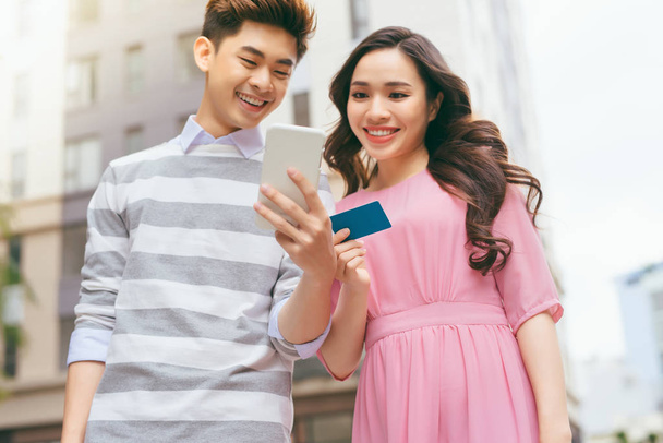Beautiful asian couple shopping with credit card in city - Photo, Image