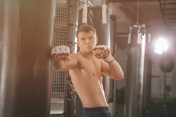 Male boxer training with punching bag in gym - Foto, Bild