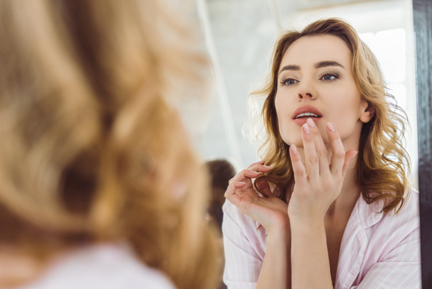 beautiful woman looking at lips in mirror reflection - Fotografie, Obrázek
