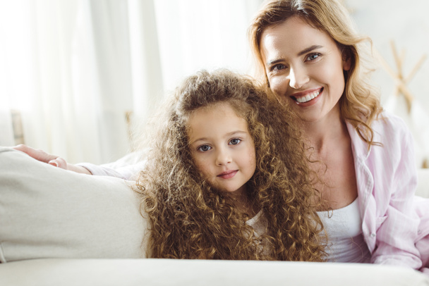 happy mother and adorable curly daughter looking at camera - Fotografie, Obrázek