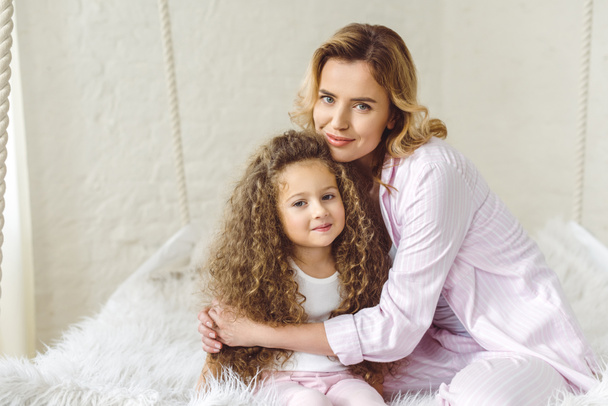 happy mother hugging her adorable curly daughter  - Valokuva, kuva