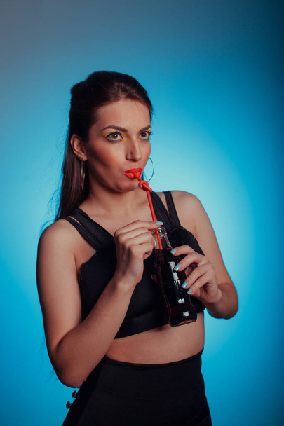 Portrait of a glamorous beautiful girl, she drinks a cola on a bright background - Фото, зображення