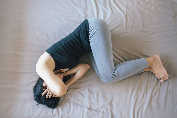 Жінка з болючим головним болем на ліжку, жінка страждає від болю в животі
 - Фото, зображення