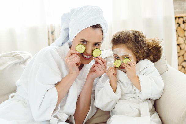 happy mother and daughter with cucumber slices doing cosmetic procedures - Photo, Image