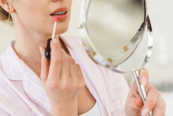 cropped view of woman looking at mirror and applying lip gloss - Φωτογραφία, εικόνα