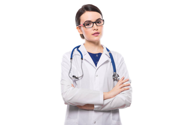 Jeune femme médecin avec stéthoscope debout avec les bras croisés et regardant la caméra
 - Photo, image