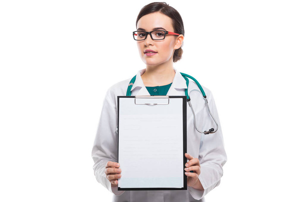 Young female doctor with stethoscope holding blank clipboard  - Zdjęcie, obraz
