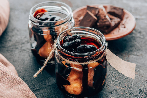 close-up view of sweet delicious homemade chocolate dessert in glass jars on black  - Foto, Imagem