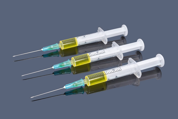 Τρεις σύριγγες με κίτρινο εμβόλιο σε σκούρο φόντο - Φωτογραφία, εικόνα