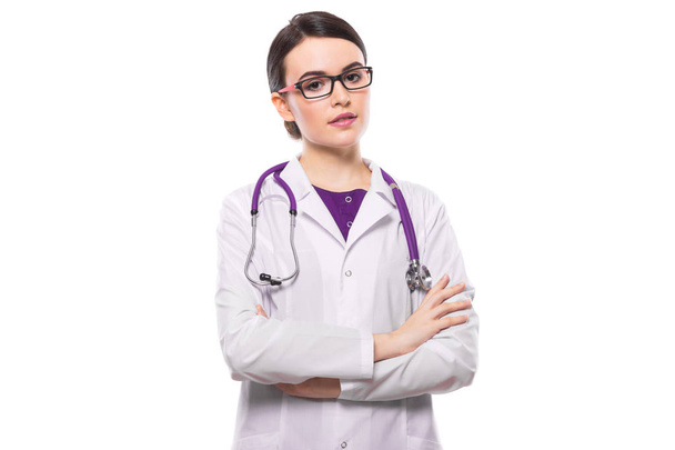 Jeune femme médecin avec stéthoscope debout avec les bras croisés et regardant la caméra
 - Photo, image