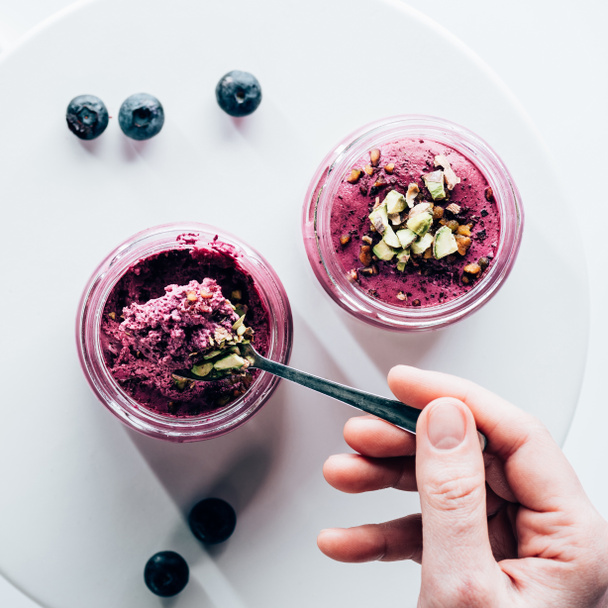 pohled shora člověk jíst chutné zdravé smoothie s cereáliemi a borůvky - Fotografie, Obrázek
