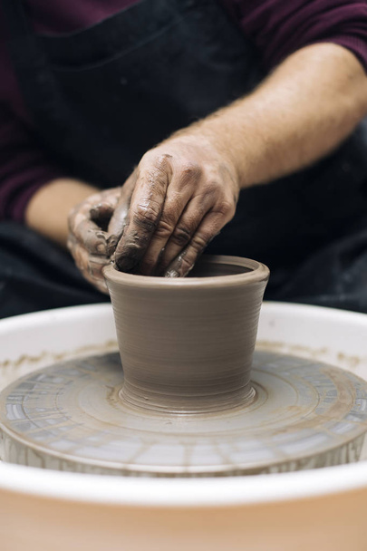 Close up detail view at an artist makes clay pottery on a spin wheel - 写真・画像