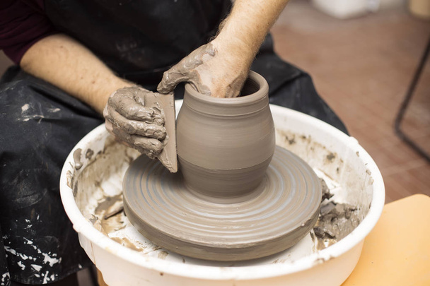 Vista de detalhe de perto em um artista faz cerâmica de barro em uma roda de giro
 - Foto, Imagem