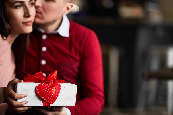 Hermosa pareja celebra el día de San Valentín en caf, jugando con corazones de juguete, compartiendo regalos y disfrutando el uno del otro
. - Foto, imagen