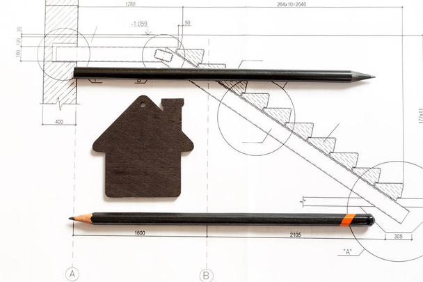 modelo preto pequeno de uma casa com lápis pretos que jaz em um bluep
 - Foto, Imagem