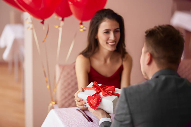 schönes verliebtes Paar im Restaurant, das Geschenke teilt und sich gegenseitig genießt, Valentinstag-Konzept - Foto, Bild