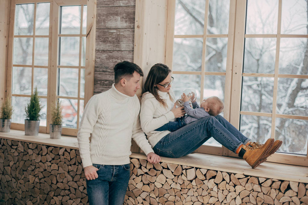 portrait of young couple with baby boy near wooden windows - Photo, Image