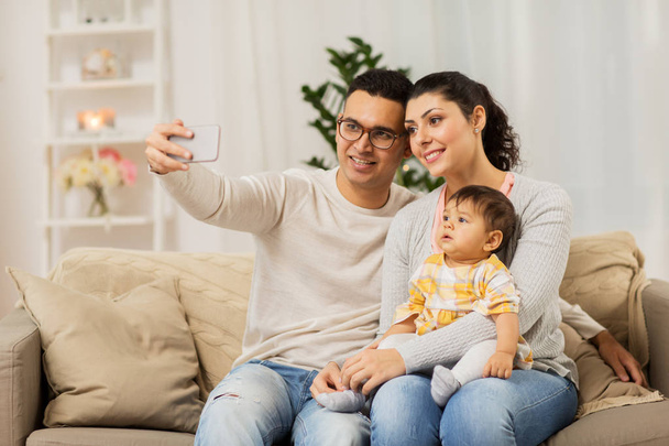 mother and father with baby taking selfie at home - Photo, Image