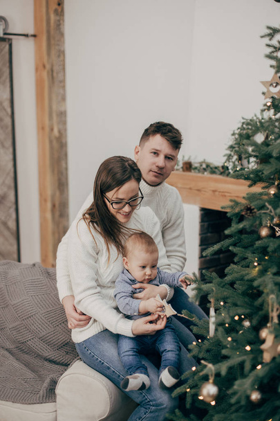 portrait of young couple with baby boy by Christmas tree  - Zdjęcie, obraz