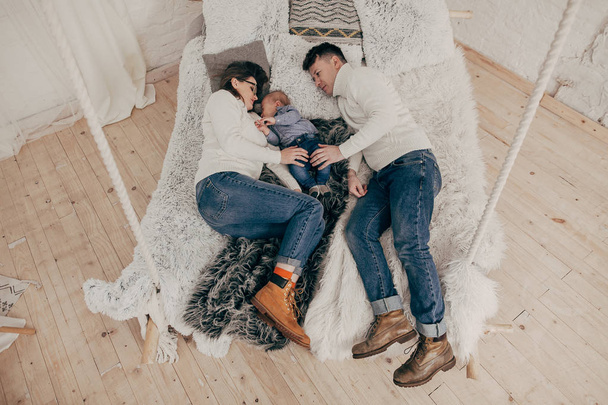 elevated portrait of young couple with baby boy lying on bed  - 写真・画像