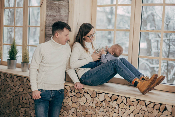 portrait of young couple with baby boy near wooden window - Foto, Bild