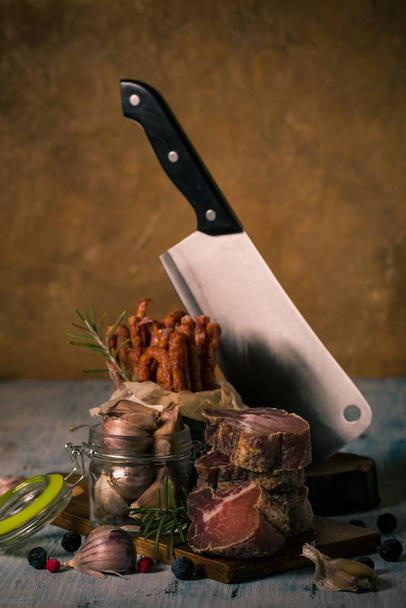 Carne italiana essiccata di cinghiale su tagliere con salsicce speziate e aglio
 - Foto, immagini