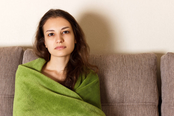Triste mujer sentada en el sofá en casa. chica cansada en el sofá está cubierto con una manta
 - Foto, imagen