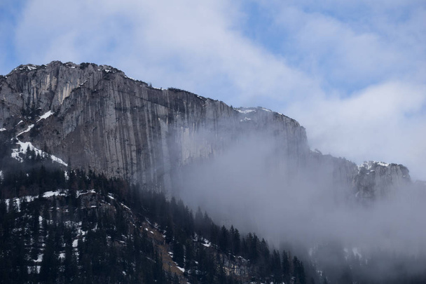 Vertical stone wall engulfed in clouds in the mountains of Austria - Foto, Bild