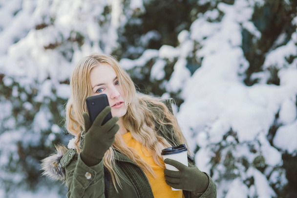 Tyttö malli poseeraa talvipuiston videopuhelut puhelin
 - Valokuva, kuva