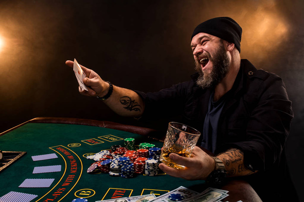 Puro ve bir casino poker masasında oturan cam sakallı adam. Kumar, iskambil ve rulet. - Fotoğraf, Görsel