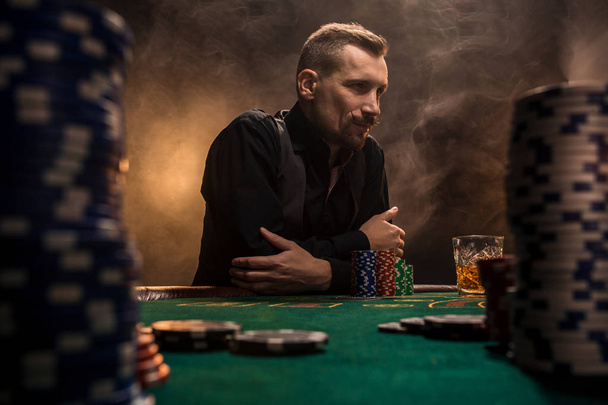 Giovane bell'uomo seduto dietro il tavolo da poker con carte e fiches
 - Foto, immagini