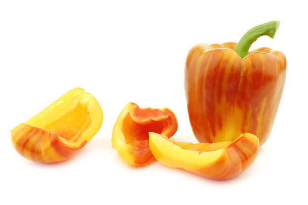 verse gele en oranje "enjoya" paprika (capsicum) en sommige gesneden stukken op een witte achtergrond - Foto, afbeelding