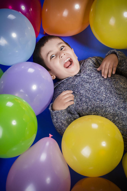Brunetka chłopiec gry z kolorowych balonów, uśmiech i radość na urodziny - Zdjęcie, obraz