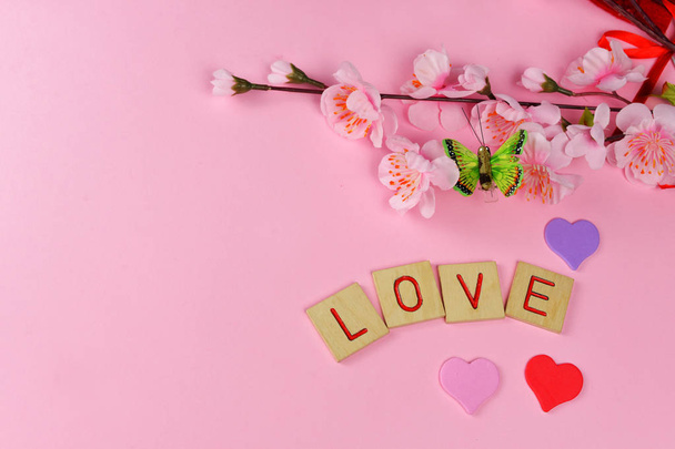bei cuori di lettere rosse con lettera d'amore, fiori e farfalla verde su uno sfondo rosa il giorno di festa di S. Valentino il 14 febbraio
 - Foto, immagini