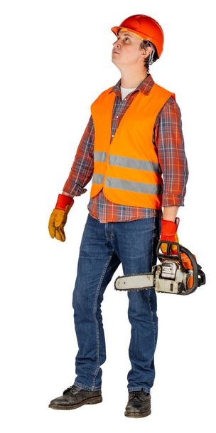 Full length portrait of a male builder in a orange helmet with chain saw over white wall background. repair, construction, building, people and maintenance concept. - Fotoğraf, Görsel