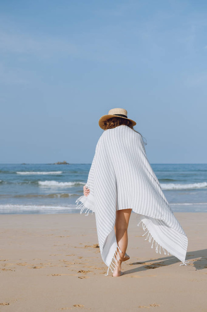 Girl in a hat walking along the beach - 写真・画像