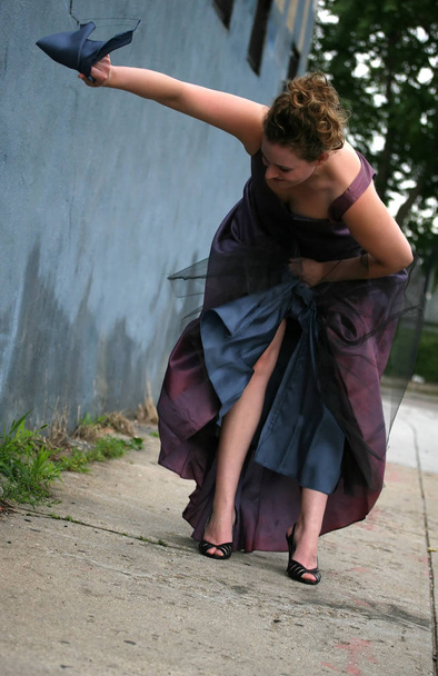 Egy nő fekete magassarkúban letépi az estélyi ruháját. - Fotó, kép