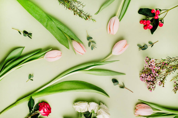 Modèle de fleurs faites de tulipes roses, roses, fleur d'hypericum sur fond vert. Couché plat, vue du dessus
. - Photo, image
