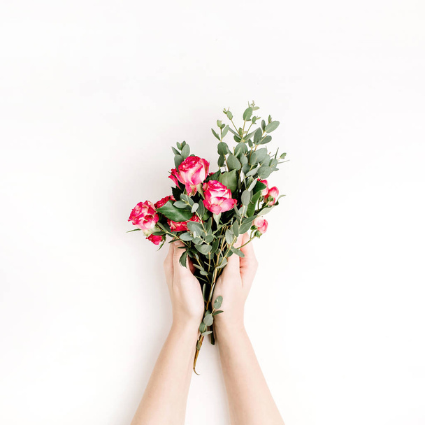 Woman hands hold rose flowers and eucalyptus branch bouquet on white background. Flat lay, top view spring hero header background. - Photo, image
