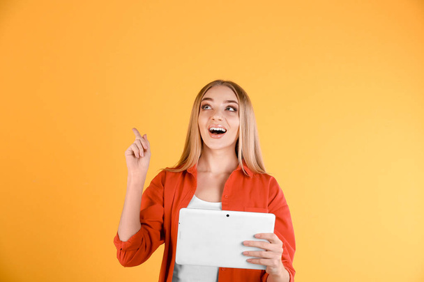 Young woman with tablet computer on color background - Φωτογραφία, εικόνα