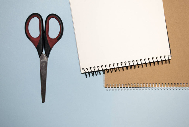 Two notepads with scissors on a blue background - Fotó, kép